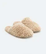 Pantufla femenina cerrada, color beige claro, con textura de pelo largo y rizado.