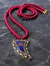 Collar de cuentas de vidrio color rojo con dije en forma de cuerno con incrustaciones de lapislázuli, coral y detalles dorados.