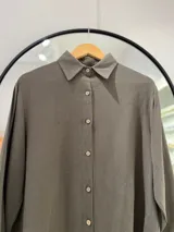Camisa clásica verde oliva, de manga larga con cuello camisero. Cierre frontal con botones de coco y laterales con abertura.