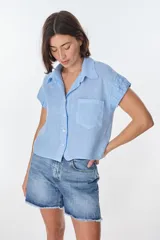 Camisa celeste de lino con cuello clásico, manga corta con detalle de frunce y bolsillo de parche en el pecho.