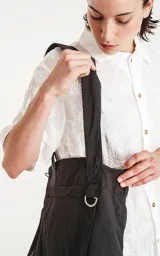 Bolso tote negro de tela técnica de microfibra de secado rápido, con espacio principal para llevar pertenencias. Cuenta con un elástico ajustable con tanca y contiene dos bolsillos, uno interno con cierre y otro externo con velcro.
