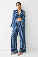 Pantalón de corte holgado en sarga con estampado a rayas verticales azules y blancas. Modelo de talle alto con cintura elástica y cordón de ajuste fino.
