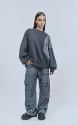 Pantalón cargo gris de corte oversize, confeccionado en tejido técnico de poliéster. Cuenta con cintura elástica, múltiples bolsillos y detalles reflectivos.
