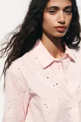 Camisa manga larga color rosa pálido con cuello solapa y cierre frontal con botones. Detalle de bordados perforados engomados con motivos florales. Corte recto.