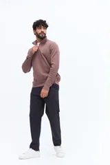 Buzo de algodón color verde musgo, con cuello alto y cierre frontal parcial. Presenta puños y cintura acanalados, y un pequeño logo bordado en el pecho.