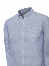 Camisa de manga larga color beige claro, confeccionada en lino orgánico. Tiene cuello abotonado, bolsillo en el pecho con logo bordado y detalles en contraste en el interior.