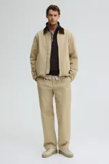 Buzo de tejido pesado color marrón oscuro, con interior cepillado suave. Presenta cuello elevado, medio cierre metálico y hombros caídos. Puños y bajo en punto acanalado.