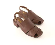 Sandalia de cuero trenzado color marrón, con punta cuadrada, taco ancho forrado en cuero y pulsera ajustable con hebilla metálica.