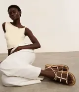 Sandalia plana dorada con tiras finas y detalle de lazos.