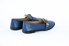 Mocasín azul con detalle de hebilla dorada.