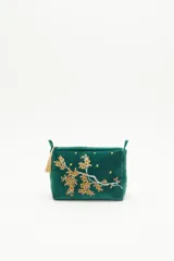 Bolso de mano tipo clutch, color verde esmeralda, de terciopelo con bordado de flores amarillas y blancas. Incluye un cierre superior y un colgante de borla dorada.