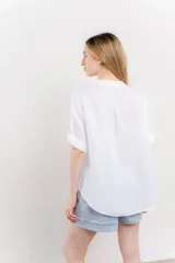 Camisa azul de lino con escote en V abotonado, bolsillo frontal y mangas 3/4 con trabilla.