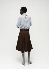 Blusa de manga larga color celeste claro con textura sutil, cuello alto con lazo largo incorporado que cae al frente.