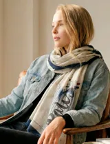 Pashmina estampada en tonos crudos y azul marino, con diseño tipográfico que incluye la palabra "Paris" y detalles de pinceladas.