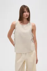 Blusa sin mangas con estampado a rayas verticales en tonos blanco, azul y verde. Presenta cuello redondo y lazos laterales.