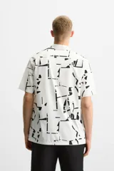 Camisa blanca con estampado abstracto en negro, de cuello bowling y manga corta.