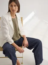 Blazer blanco de lino con corte estructurado, solapa con pespuntes y bolsillos con solapa.