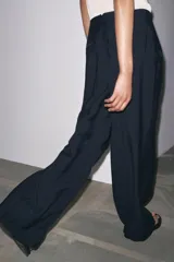 Pantalón de tiro medio color celeste confeccionado en hilatura con mezcla de lyocell. Tiene bolsillos laterales, pinzas delanteras, pierna ancha y cierre frontal con cremallera y botón.