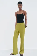 Pantalón de vestir color verde oliva, de tiro medio, corte flare y bolsillos laterales.