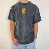 Remera azul con efecto gastado, corte oversize y estampa trasera con un sol amarillo dentro de un cuadrado negro y texto "This is living" y "Sunsets sessions".