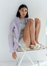 Camisa oversize lila con rayas verticales, de manga larga con puños abotonados, cuello camisero y dos bolsillos de parche en el pecho.