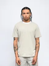 Remera color arena de corte clásico con cuello redondo ribeteado en blanco y logo Umbro estampado en el pecho.