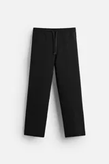 Pantalón negro de corte recto confeccionado en tejido interlock de algodón con elasticidad. Tiene cintura elástica ajustable con cordón, bolsillos frontales y bolsillos traseros de vivo.
