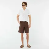 Camisa blanca de lino con cuello mao, manga corta con dobladillo y cierre frontal con botones.