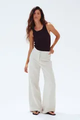 Pantalón sastrero color crema en tejido liviano de mezcla de lino y viscosa con pinzas adelante y atrás. Modelo de tiro alto con cierre, botón nacarado y piernas amplias.