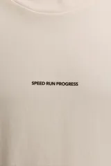 Camiseta color crudo de corte relaxed fit, cuello redondo y manga corta. Estampado con la frase "Speed Run Progress" en el frente y texto en la espalda.