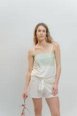 Conjunto de pijama color blanco, compuesto por musculosa con escote recto y detalle de puntilla elastizada en verde agua, y short con elástico y lazo en la cintura.