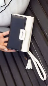 Billetera mediana marca Lincoln's confeccionada en cuero sintético con diseño bicolor. Presenta una tapa en tono dorado metalizado con cierre de presilla y cuerpo negro con compartimento de cremallera. Cuenta con múltiples divisiones internas para tarjetas, billetes y monedas, además de una práctica correa de mano.