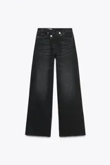 Pantalón de jean negro de tiro alto, corte wide leg y largo hasta el tobillo. Presenta un diseño asimétrico en la cintura con cierre de cremallera y botones metálicos.