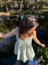 Musculosa de algodón con estampado a cuadros vichy en tonos celeste y amarillo, con breteles finos y detalle de volados en el ruedo.