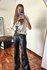 Pantalón Oxford negro de cuero sintético con cierre frontal y aberturas laterales con pasamanería plateada.