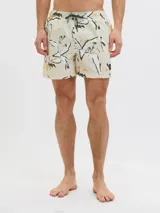 Short de baño color crema con estampado de flores y hojas en blanco, negro y amarillo. Tiene cintura elástica con cordón ajustable, bolsillos laterales y un bolsillo trasero.