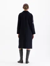 Tapado largo de paño color azul marino con bordados de piedras color cristal en forma de cerezas y pájaros. Posee cuello de solapa, cierre frontal con botones y bolsillos laterales.