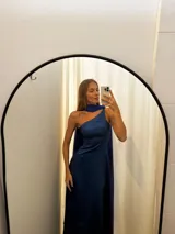 Vestido largo de tafeta con brillo, color gris o plateado, con escote asimétrico de un solo hombro y una pieza de seda liviana que cae como una capa o chal.