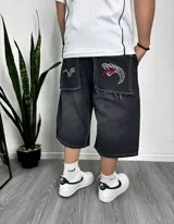 Bermuda de jean negro con efecto lavado, corte ancho y largo a la rodilla. Bolsillos traseros con apliques de tela con bordados de serpientes.