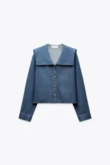 Camisa celeste de algodón con efecto denim, cuello bobo, escote pico, manga larga con puños y cierre frontal con botones.