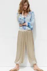Pantalón bombacho color beige de tiro alto, con elástico en la cintura y en los tobillos.