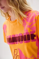 Remera color naranja con estampado floral en tonos rosa y fucsia, con la palabra "LAMODE" en relieve y contorno de labios.