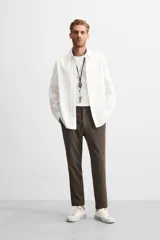 Pantalón slim fit negro confeccionado en tejido con elasticidad en ambas direcciones. Cuenta con bolsillos frontales y traseros de vivo con botón. Cierre frontal con cremallera y botón.