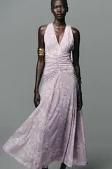 Vestido largo de tul color lila con estampado de flores blancas, cuello halter con lazada y escote pico.