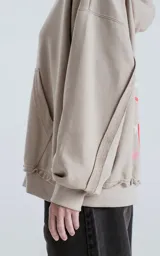 Buzo con capucha color beige, con costuras expuestas, calce oversize crop y la palabra "AMOR" estampada en el pecho.