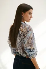 Camisa celeste con estampado abstracto en tonos marrones y azules, de corte clásico, cuello camisero y mangas largas con puños abotonados.