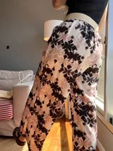 Pantalón palazzo con estampado floral en tonos blanco, negro y beige, con cintura elástica.