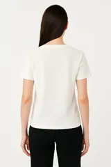 Remera blanca de algodón con estampado de flores azules y naranjas, de corte clásico y cuello redondo.