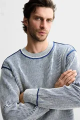 Jersey de punto con cuello redondo y manga larga. Diseño a rayas verticales en color azul marino y blanco.