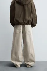 Pantalón de jean color beige, de corte amplio y tiro alto, con cinco bolsillos, efecto lavado y cierre frontal con botones.